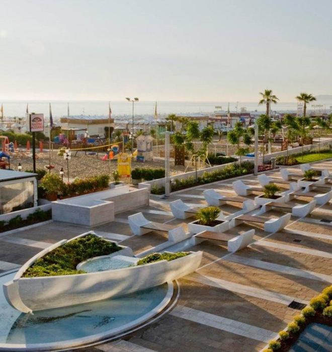 Vista sul mare con panchine moderne e giardino.