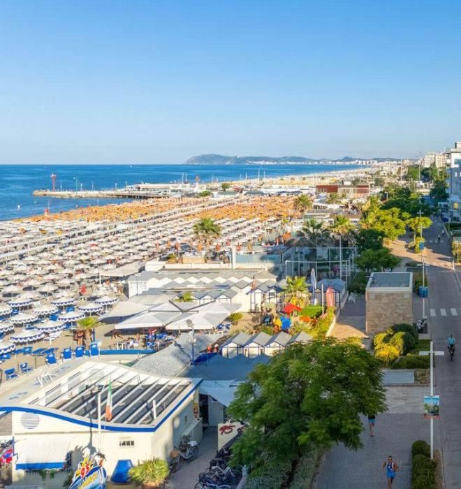 Spiaggia affollata con ombrelloni colorati e mare blu.