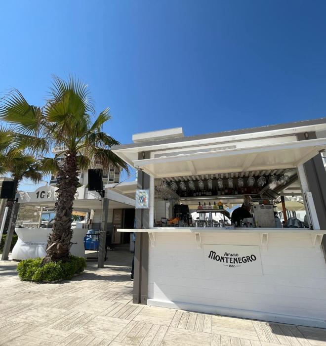 Chiosco sulla spiaggia con palme e cielo azzurro.