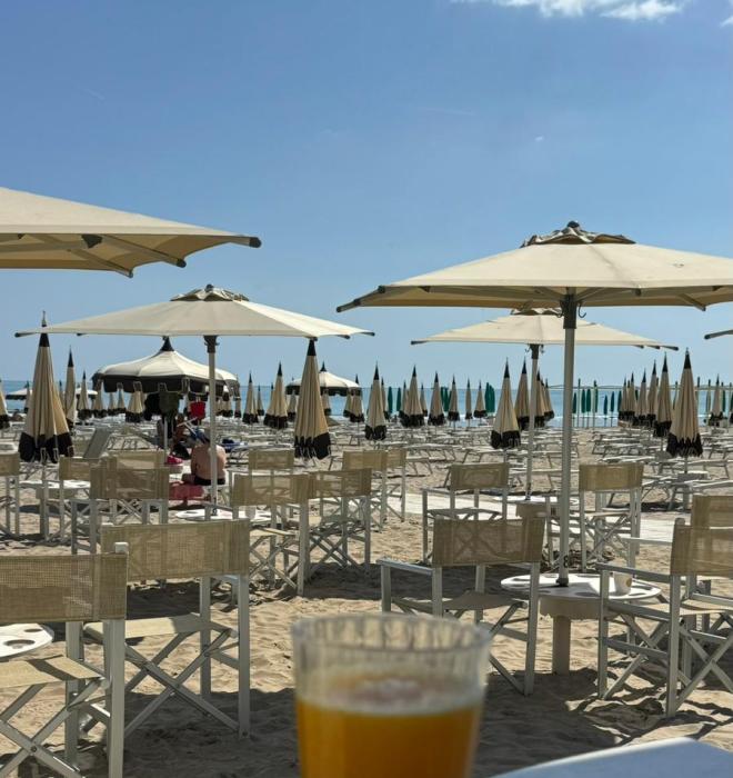 Spiaggia soleggiata, sedie vuote, ombrelloni e bevande fresche. Relax estivo perfetto.