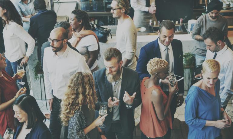 Gruppo di persone socializza a un evento con drink in mano.
