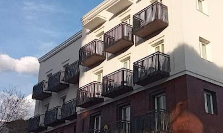 Edificio moderno con balconi, cielo azzurro sullo sfondo.