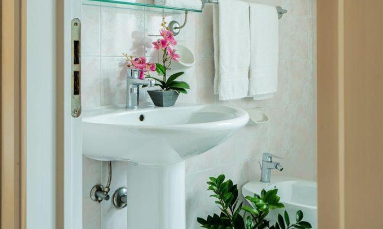 Bagno luminoso con piante e asciugamani bianchi.