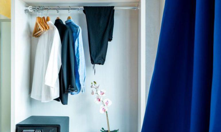 Armadio aperto con vestiti, cassaforte e pianta.