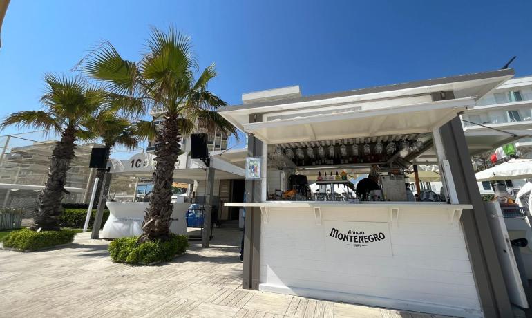 Chiosco sulla spiaggia con palme e cielo azzurro.