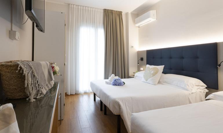 Camera moderna con letto matrimoniale e TV a parete.