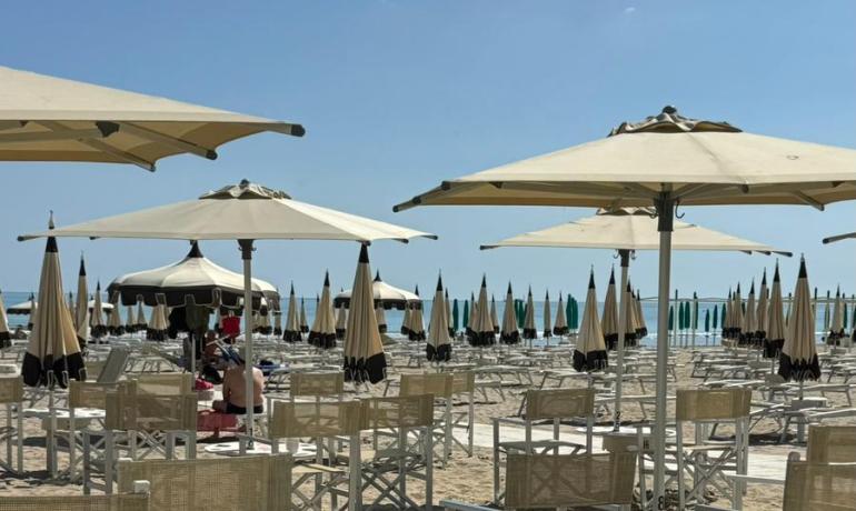 Spiaggia soleggiata, sedie vuote, ombrelloni e bevande fresche. Relax estivo perfetto.