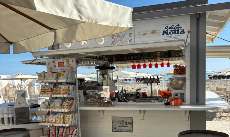 Chiosco estivo sulla spiaggia, sole splendente e atmosfera rilassante.