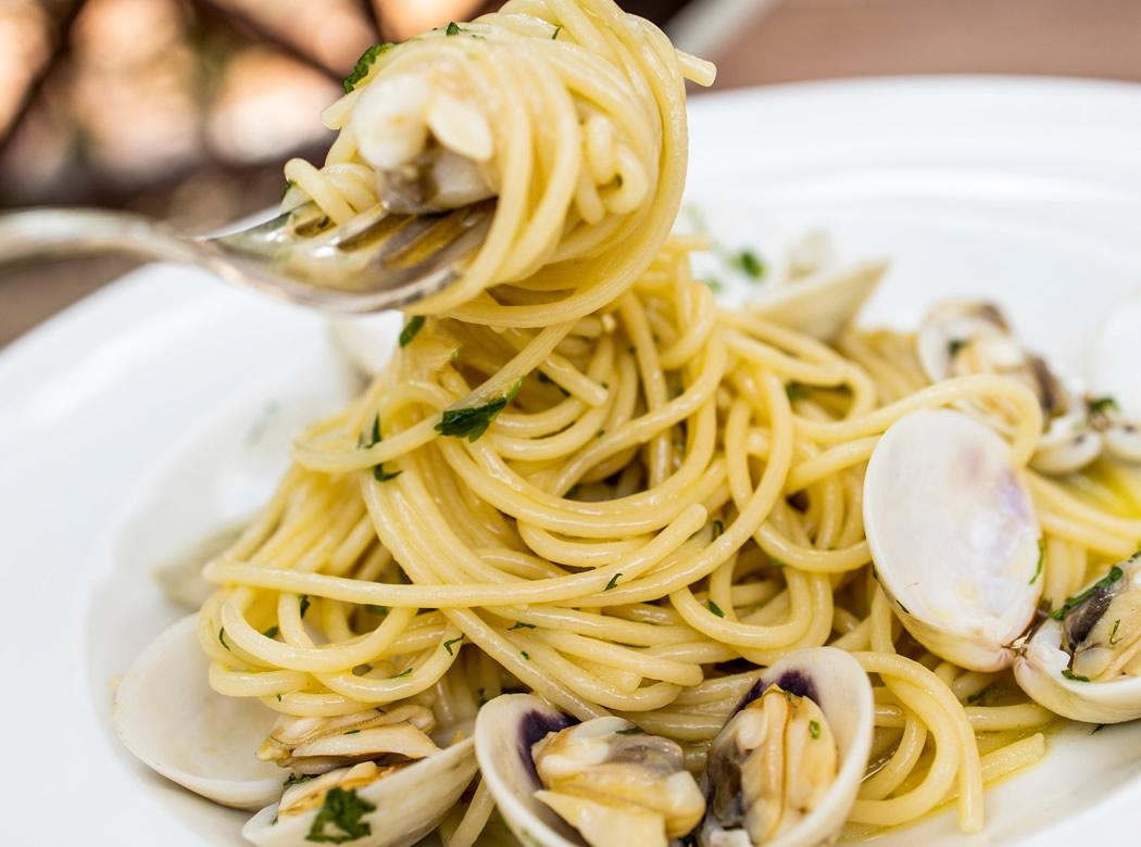 Ristorante luminoso con tavoli apparecchiati, sedie bianche e ampie finestre.