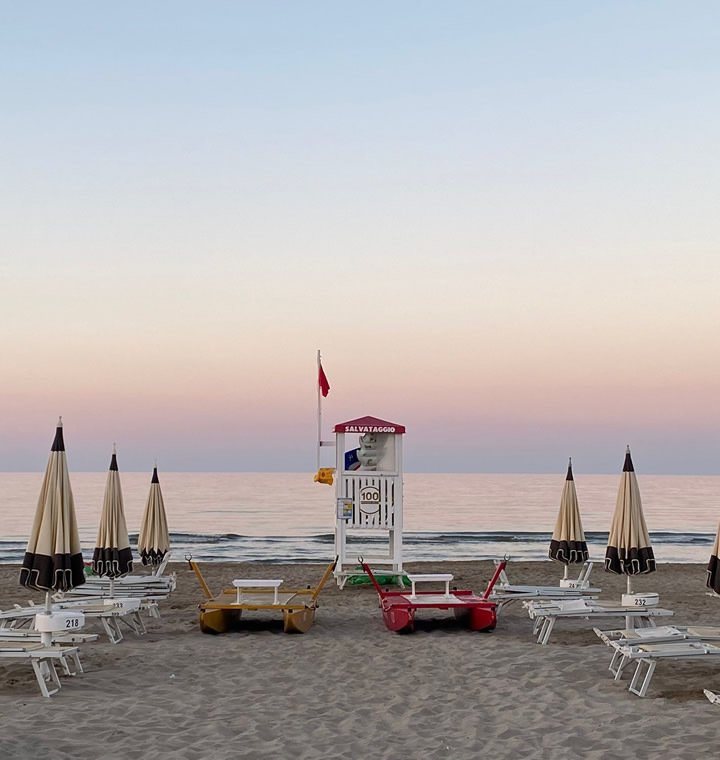 Famiglia felice corre in spiaggia, spruzzi d'acqua e sole estivo.