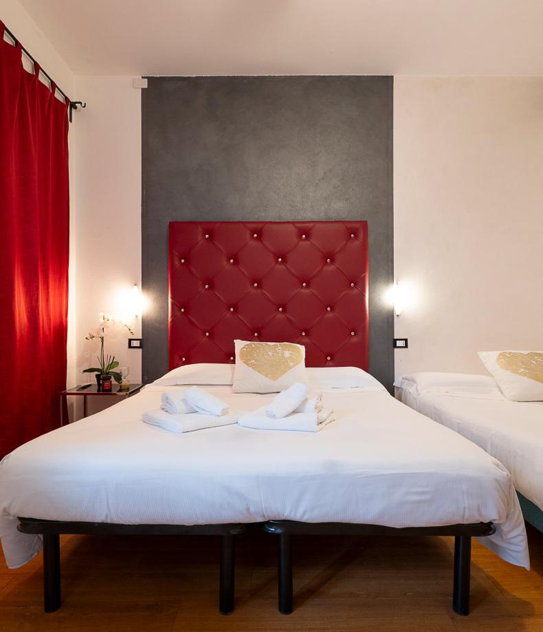 Camera moderna con testiera rossa, cuscini decorati e copriletto blu.